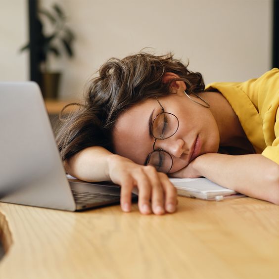 A girl sleeping on the table with her laptop by side. 